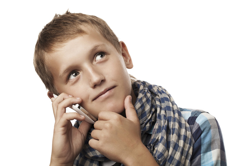 Ein Junge hält sein Smartphone am Ohr und denkt nach.